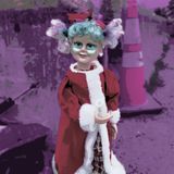 A strange doll with Christmas clothing holding a rolled-up piece of paper. The doll has brightly colored hair and makeup and is standing in front of a dumpster.