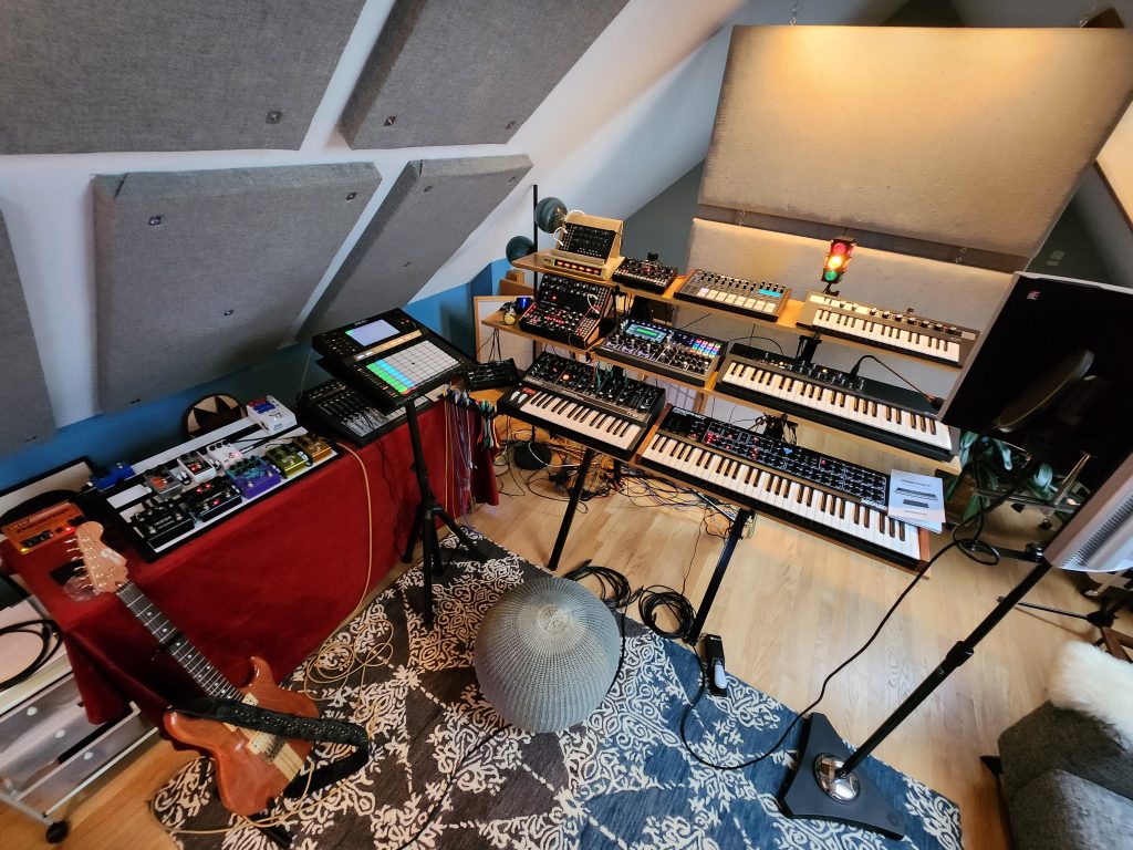 My current instrument setup, including 9 synthesizers, one drum machine, an Akai Force for controlling Ableton, a pedal board, and an electric guitar.