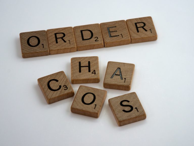 Scrabble tiles spelling the words "order" in a neat row and "chaos" in a messy pile