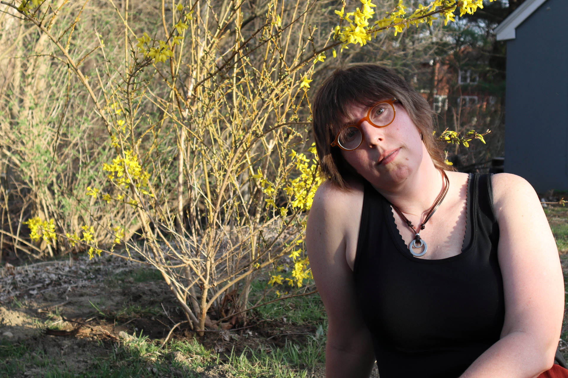 Alison Wilder in front of a just-blooming forsythia bush in April 2023