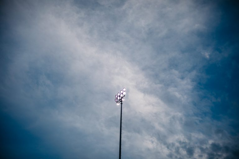 A stadium light against a lightly clouded sky